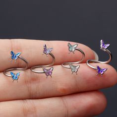 a person is holding five butterfly rings in their hand