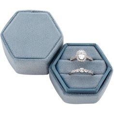 two engagement rings in a blue velvet ring box with diamond accents on each band and an oval - shaped, beveled edge