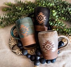 three coffee mugs sitting on top of a table next to some berries and greenery