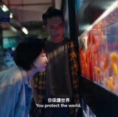 two people standing next to each other looking at something in a glass case that says you protect the world