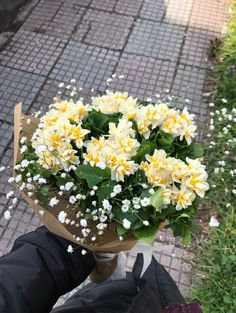 a bouquet of yellow and white flowers in someone's hand