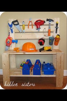 a wooden work bench with tools and construction equipment on it's shelf, in front of a wall