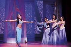 a group of women standing on top of a stage in front of a purple curtain