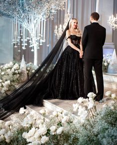 a man and woman standing next to each other in front of a stage with chandeliers