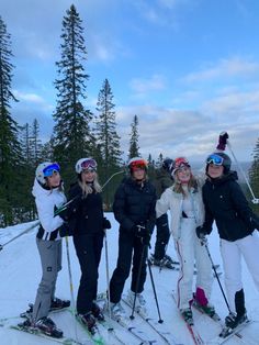 four people on skis posing for a photo in the snow with trees behind them