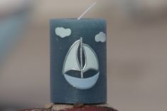 a candle with a sailboat painted on it sitting on top of a brick wall