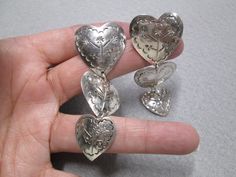 "Gorgeous sterling silver triple heart dangle earrings. Beautifully designed with nice stampings. They measure 3\" long, with the largest heart being 1 1/8\" wide. Well made, but quite light on your lobes, weight = 17.6gms. These are made in Mexico in the late 70's, stamped TX, Mexico, 925. Of course they have also been tested for purity. New old stock, in good vintage condition. A great earring at a great price. KEEP*IN*TOUCH Please LIKE and FOLLOW us on www.facebook.com/vintageturquoiseandmore Sterling Silver Heart Earrings, Mexican Earrings, Triple Heart, Silver Heart Earrings, Turquoise Drop Earrings, Earrings Heart, Heart Dangle Earrings, Long Dangle Earrings, Genuine Turquoise