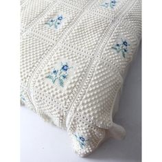 a white crocheted pillow with blue flowers on it's sides and the bottom