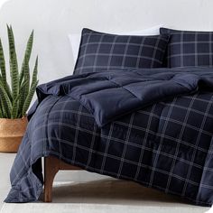 a black and white checkered comforter on a bed next to a potted plant