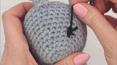 a person holding a crocheted object in their hands with pink nail polish on it