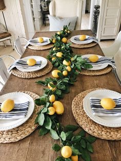 the table is set with lemons and greenery on it, along with place settings