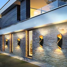 an exterior view of a modern house with stone walls and lights on the outside wall