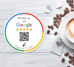 a cup of coffee next to a sticker that says review us on google and has a qr code