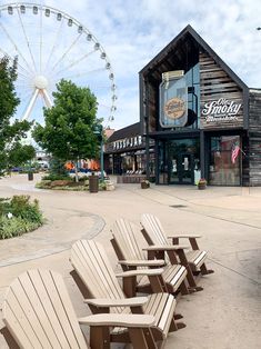 several wooden benches lined up in front of a building with a ferris wheel behind it