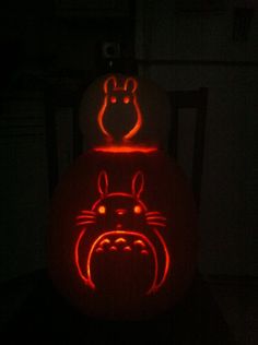 a carved pumpkin with an image of totoro on it's face in the dark