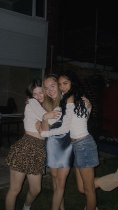 three girls hugging each other outside at night