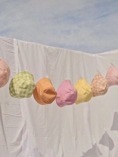 several hats are hanging on a clothesline with the sky in the backround