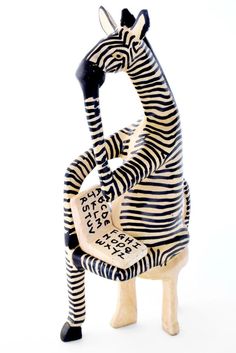 a zebra sitting on top of a wooden chair with writing on it's legs