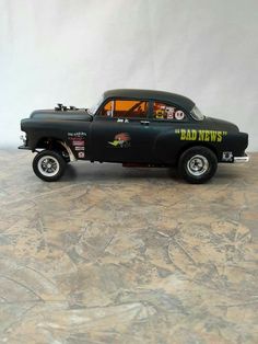 a toy car is sitting on the floor in front of a white background with black lettering