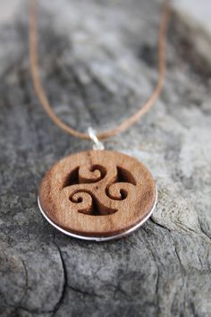 "This beautiful and unique hand-carved Triskelion pendant will be made for you, or a loved one, in my studio on the West of Ireland. Encircled with a Sterling silver ring into a side groove, this intricate carving features a piece of elm. Considered one of the sacred trees in the Celtic world, elm has often been associated with Mother and Earth Goddesses. In rural Ireland the elm tree was said to possess magical properties and was considered to be the home of the fairies. Found inscribed on mega Nature-inspired Carved Natural Jewelry, Brown Spiral Jewelry As A Gift, Symbolic Carved Brown Jewelry, Nature-inspired Carved Round Pendant Jewelry, Rural Ireland, Intricate Carving, Triple Spiral, Elm Tree, Sacred Tree