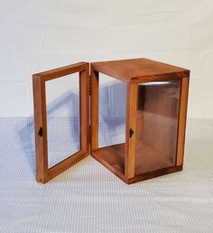 an open wooden box sitting on top of a white table next to another small piece of wood