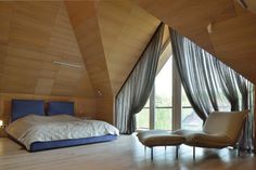 a bedroom with a bed and two chairs in front of a large window that looks out onto the outdoors