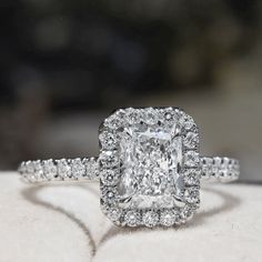 an engagement ring with a cushion cut diamond surrounded by pave diamonds