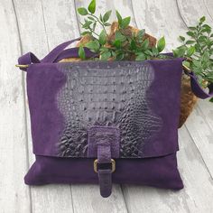 This snake print style bag comes in black or purple. has been made in Italy from quality, soft suede leather and has a long 60cm adjustable strap which makes it an ideal crossover body bag. It is a fully lined bag with one internal zip pocket. It also has a zip pocket on the rear of the bag. Full features of this beautiful bag, include: * Flap Over Zipper, which is great for security * Closure on top * Old gold tone metal hardware * Outer back zipped pocket * Internal zipped pocket * Snake skin detail on front * Soft Real Suede leather * Fully lined inside * Handle drop: 60cm * Dimensions: H28cm x W29cm x D4cm * Material: leather and mixed metals This suede bag has been made in Italy by artisans from genuine suede and the quality is clear to see. Due to the individual nature, the shade of Purple Leather Satchel Bags, Purple Leather Tote Shoulder Bag, Purple Leather Bags With Removable Pouch, Purple Leather Rectangular Bag, Purple Leather Bag For Daily Use, Purple Soft Leather Bag, Purple Leather Satchel With Removable Pouch, Purple Leather Satchel, Soft Leather Purple Shoulder Bag