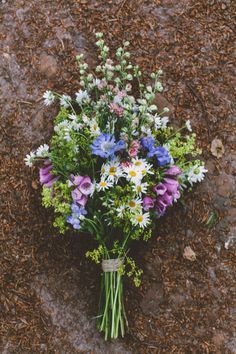 a bouquet of wildflowers and daisies in a vase sitting on the ground