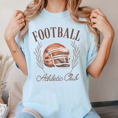 Gear up for game day with our Football Athletic Club Comfort Color Tee. Crafted for comfort and style, this tee is perfect for fans who want to show their support in a laid-back yet spirited way. Emblazoned with the emblem of our Football Athletic Club, this tee exudes team spirit and camaraderie. Whether you're cheering from the stands or watching from home, our tee ensures you'll be representing your team in style. Made from premium materials, this tee offers unparalleled comfort and durabilit Sports Fan T-shirt For Baseball Season, Collegiate Graphic Print T-shirt For Game Day, Collegiate Game Day T-shirt With Team Name, Collegiate T-shirt For Football Season Fan Merchandise, Varsity T-shirt With Team Logo For Football Season, Game Day Sports Fan T-shirt With Crew Neck, Collegiate Style T-shirt For Football Season Fan Merchandise, Collegiate Style T-shirt For Football Season, Sports Fan T-shirt With Team Logo For Baseball Season