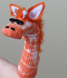 a giraffe toy is being held up by someone's hand with it's fingers