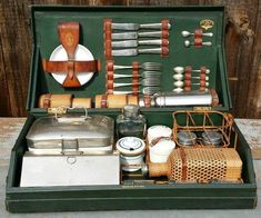 an open green box with various kitchen utensils and other items in it on a table