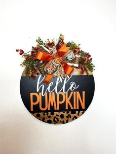 a hello pumpkin sign hanging from the side of a white wall with an orange bow