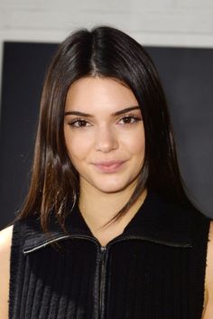 a close up of a person wearing a black jacket and looking at the camera with a smile on her face