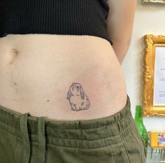 a woman's stomach with a tattoo of a dog on the lower part of her belly