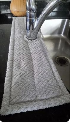 a kitchen sink with a silver faucet next to a towel on the counter