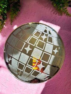 the reflection of a person's feet in a round mirror on a pink wall