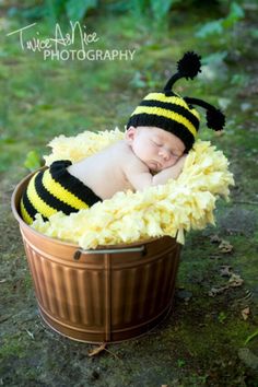 a newborn baby wearing a bee costume sleeping in a bucket