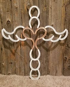 a cross made out of horseshoes sitting on top of a wooden fence next to a wall