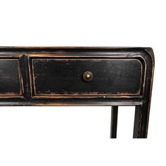 an old black wooden table with two drawers on one side and brass knobs on the other