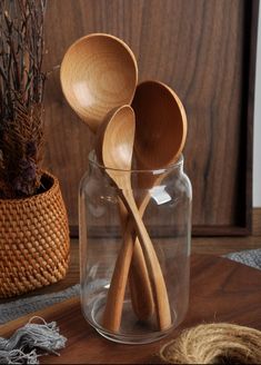 three wooden spoons in a glass jar on a table