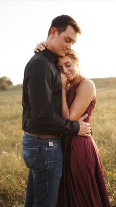 a young man and woman embracing each other in the middle of a field with tall grass