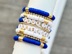 Personalized stretchy bracelets with YOUR team colors!  Add a Gold Brass Plated Barrel Bracelet (or two! or three!) to create your own personalized stack!  👉🏻 Each bracelet sold separately 👉🏻 All bracelets are hypoallergenic 1. Measure your wrist and select size from drop down menu. (See photo for measurement instructions.) 2. Select which bracelet(s) you want to purchase from the BRACELET OPTIONS in the dropdown menu.  3. Complete the PERSONALIZATION section for each color block brass bracelet and/or word bracelet.   - COLORS - WORD(S) 📦📫FREE SHIPPING ON ALL DOMESTIC ORDERS OF $35 OR MORE! 📌Care:  Keep bracelets dry and away from chemicals. Roll bracelet on instead of stretching over hand. Bracelets may break with excessive over-stretching. 📌Since each bracelet is made to order, a Hand Bracelets, Keep Bracelet, Team Bracelets, Bracelet Colors, Color Bracelet, Word Bracelet, Brass Bracelet, College University, Personalized Gifts For Her