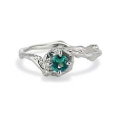 a white gold ring with a green stone in the center and two leaves on each side