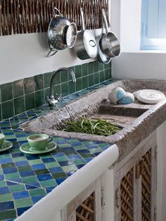 a kitchen sink with pots and pans hanging on the wall next to it's counter