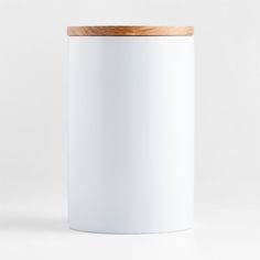 a white canister with a wooden lid on a white surface, viewed from the front