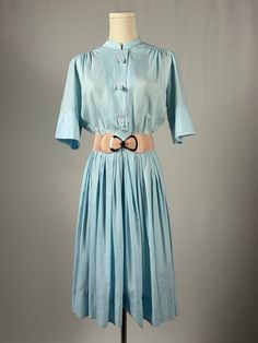 Baby blue Pacemaker Junior dress has so many lovely features. This dress features embroidered fleur di lis with loops that cover buttons.  Valoumonous stacked knife pleats and cross over skirt with snap closure.  (Belt pictured is not included) Good condition Has mild pilling and one very small spot on front.  Original belt is also missing. Measures Bust 19" Waist 14" Length shoulder to hem 40" Please keep in mind that when buying vintage items, you are purchasing something that has been pre-loved.  Most vintage items show some blemishes, imperfections, and wear, but that is also what makes them so unique.  We do our best to photograph/disclose the condition of the item as best we can.  Vintage items are at least 20 years old.  Prices reflect condition, age and quality.  Items are sold as Button-up Daywear Dress With Pleated Waist, Daywear Pleated Collared Shirt Dress, Fitted Button-up Shirt Dress With Pleated Waist, Daywear Full Pleated Skirt Dress, Collared Pleated Shirt Dress For Daywear, Collared Shirt Dress With Pleated Waist For Daywear, Pleated Collared Shirt Dress For Daywear, Summer Dresses With Stand Collar And Buttons, Fitted Pleated Daywear Dress