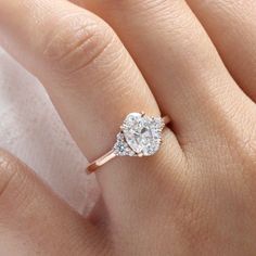 a woman's hand with a diamond ring on top of her finger and the other hand holding an engagement ring