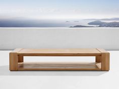 a wooden coffee table sitting on top of a white floor next to an ocean view