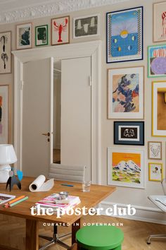 a room with many pictures on the wall and a table in front of it that has a green stool